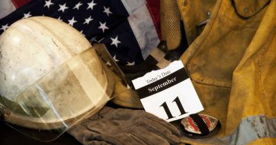Hardhat, flag, police badge and firefighter jacket with September 11 calendar page