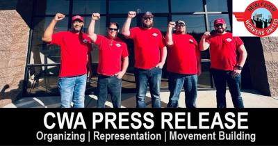 A group of IUE-CWA members with raised fists wearing red shirts.