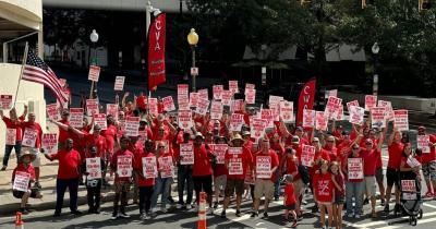 Large group of workers wearing red and holding On Strike Against AT&T signs