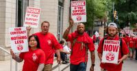 four workers wearing red t-shirts holding Fair Contract or Nothing Less signs