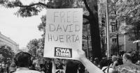 black and white phot of a hand holding a sign that reads Free David Huerta CWA Strong